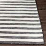 Tapis rayé noir et blanc sur plancher en bois.