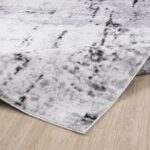 Tapis moderne gris et blanc sur plancher en bois.