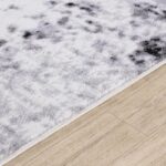 Tapis moelleux gris et blanc sur parquet.