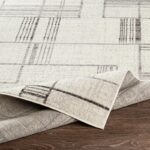 Tapis beige à motifs géométriques sur plancher bois.