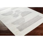 Tapis moderne blanc motifs géométriques sur sol en bois.