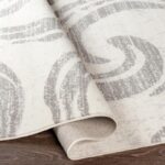 Tapis beige enroulé au motif géométrique.