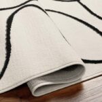 Tapis moderne enroulé sur plancher en bois.
