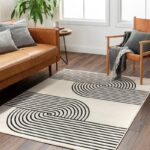 Salon moderne avec canapé cuir et tapis graphique.