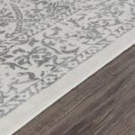 Tapis gris et blanc à motifs sur plancher bois.