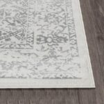 Tapis gris et blanc à motifs, sol en bois.