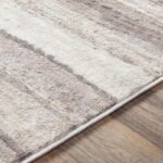 Tapis rayé beige et gris sur plancher en bois.