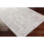 Tapis gris vintage sur parquet brun.