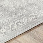 Tapis doux gris avec motif vintage sur parquet.