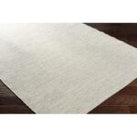 Tapis beige texturé sur parquet brun.