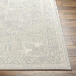Tapis beige à motifs sur parquet.