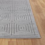 Tapis gris motifs géométriques sur parquet.