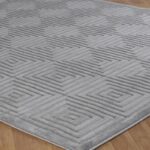 Tapis gris à motifs géométriques sur sol en bois.