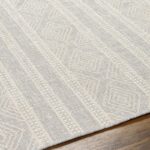 Tapis beige à motifs géométriques sur plancher bois.
