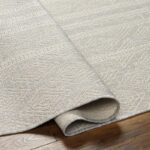 Tapis texturé beige sur parquet en bois.