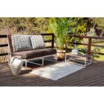 Terrasse avec canapé, table basse et plante verte.