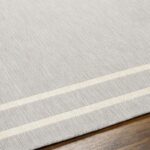 Tapis gris bordure blanche sur plancher en bois