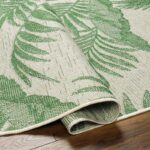 Tapis motif feuilles tropicales sur sol en bois.
