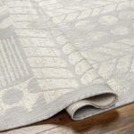 Tapis beige design géométrique sur parquet.