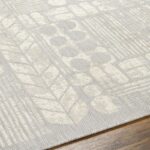 Tapis beige à motifs géométriques sur plancher en bois.