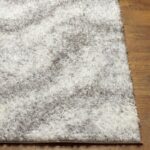 Tapis moelleux blanc sur plancher en bois.