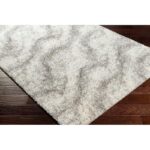Tapis moelleux blanc sur plancher en bois.