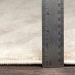 Règle métallique mesurant épaisseur de tapis.