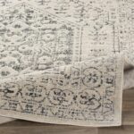 Tapis beige à motifs traditionnels sur plancher bois.