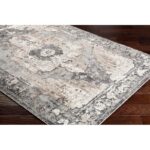 Tapis vintage gris et beige sur plancher en bois.
