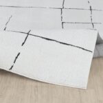 Tapis moderne blanc avec motifs géométriques noirs.