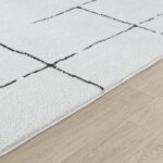 Tapis blanc motifs géométriques sur plancher bois.