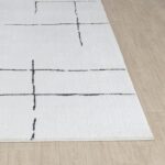 Tapis blanc motifs géométriques noirs sur parquet.