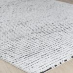 Tapis moderne blanc avec motifs géométriques noirs.