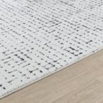 Tapis blanc motif géométrique sur plancher bois.