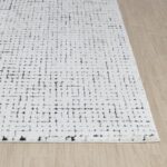 Tapis moderne blanc avec motifs géométriques noirs.