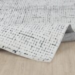 Tapis moderne blanc à motifs géométriques noirs.