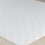 Tapis blanc texturé sur sol en bois.