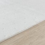 Tapis blanc moelleux sur parquet clair.
