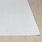 Tapis blanc doux sur plancher en bois.