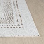 Tapis blanc motifs géométriques marron sur parquet clair.