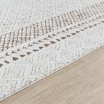 Tapis berbère blanc motifs géométriques marron sur sol.