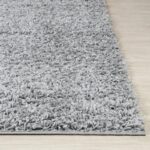 Tapis moelleux gris sur sol en bois.