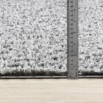 Tapis gris mesuré avec une règle métallique.