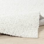 Tapis blanc texturé sur plancher en bois.