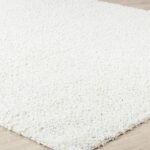 Tapis blanc moelleux sur sol en bois.