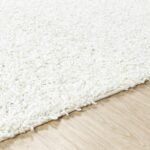 Tapis blanc moelleux sur parquet clair.