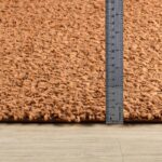 Règle sur tapis orange mesurant l'épaisseur.