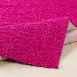 Tapis shaggy rose sur parquet.