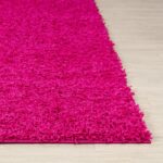 Tapis rose texturé sur sol en bois.