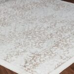 Tapis beige à motifs orientaux sur parquet.